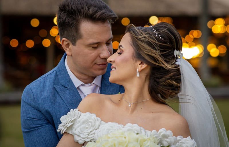 Casal de noivos em momento romântico iluminado pelas luzes da festa