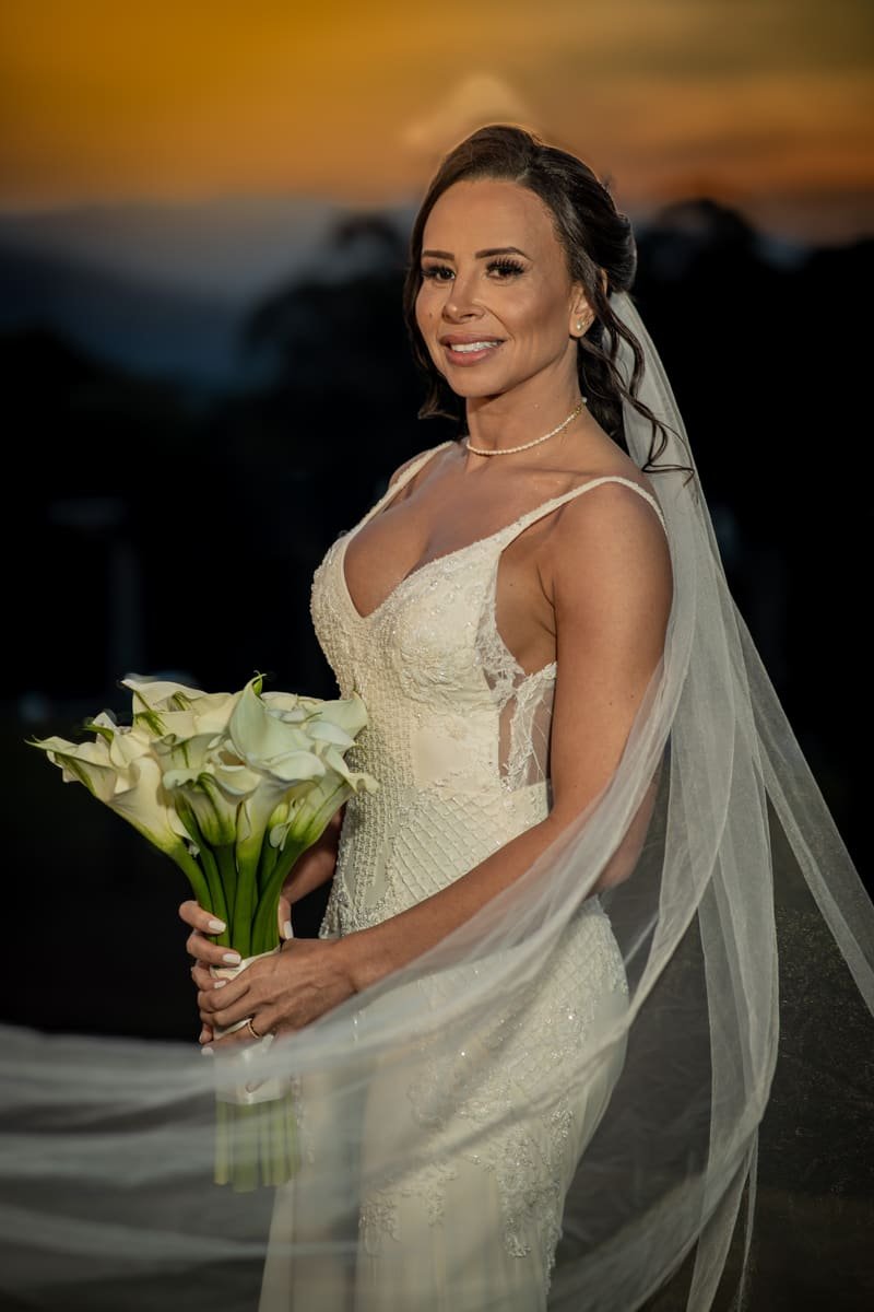 Noiva sorridente com buquê de flores no entardecer durante a festa